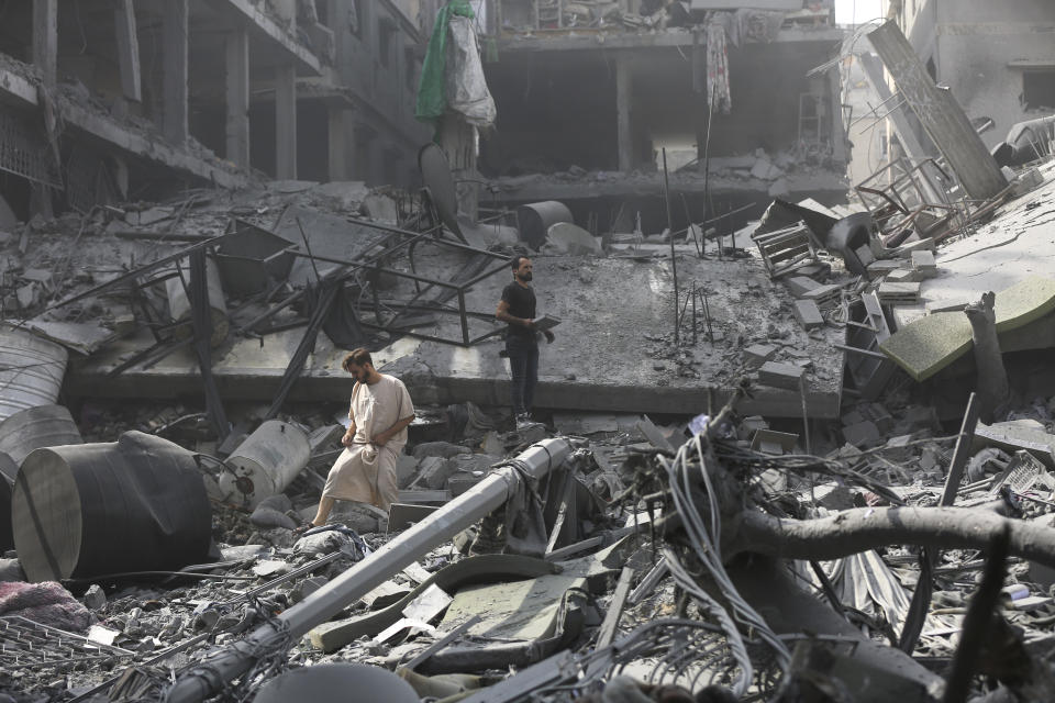 Palestinos inspeccionan los daños de edificios destruidos tras los ataques aéreos israelíes sobre Ciudad de Gaza, el lunes 23 de octubre de 2023. (AP Foto/Abed Khaled)