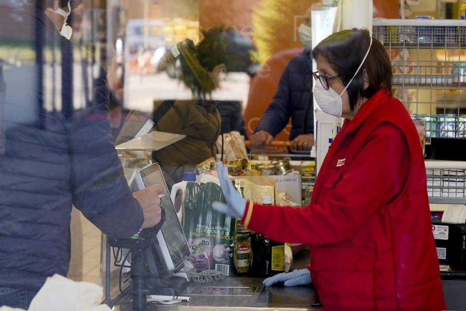 A cashier wears a sanitary mask as she talks to a client in a supermarket in Casalpusterlengo, Northern Italy, Monday, Feb. 24, 2020. Italy scrambled to check the spread of Europe's first major outbreak of the new viral disease amid rapidly rising numbers of infections and a third death. Road blocks were set up in at least some of 10 towns in Lombardy at the epicenter of the outbreak, including in Casalpusterlengo, to keep people from leaving or arriving. (AP Photo/Paolo Santalucia)