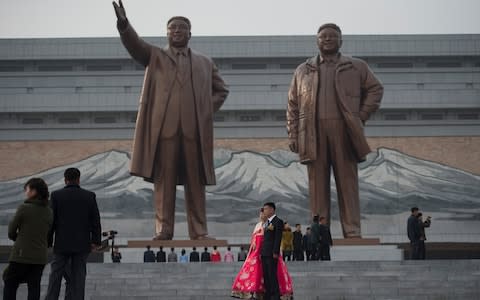 Wedding groups gather at the Korean Revolution Museum to lay flowers at the statues of Kim Il-Sung and Kim Jong-Il  - Credit: Eddie Mulholland