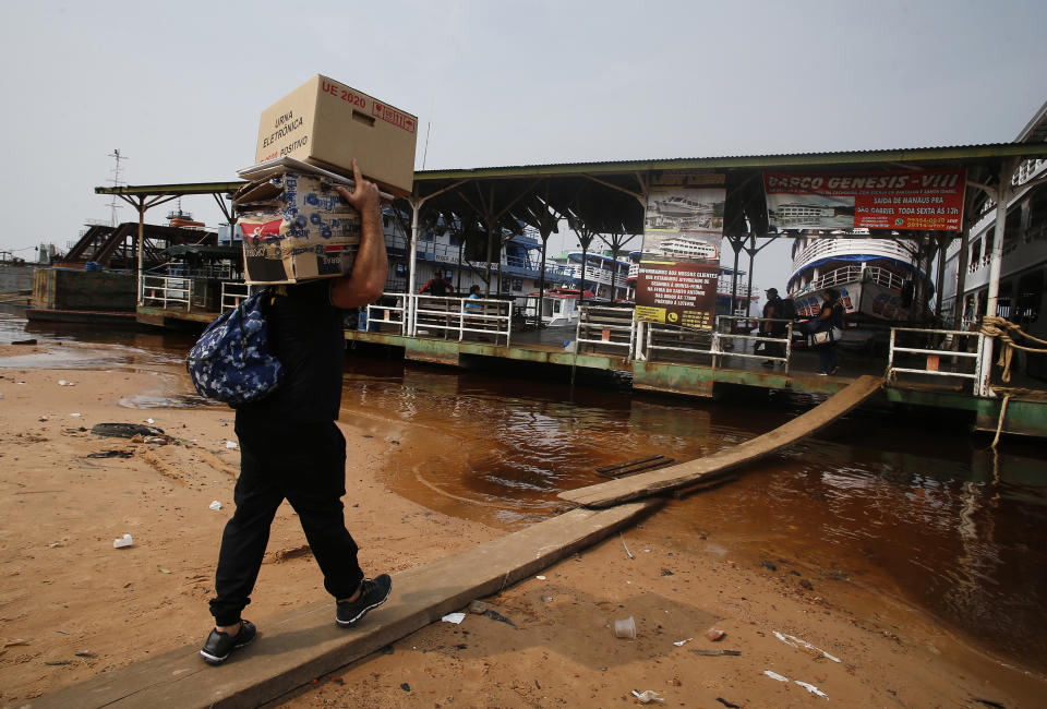An electoral worker carries an electronic voting machine to be taken by boat to voting centers ahead of tomorrow's elections at the Sao Raimundo port, Manaus, Amazonas state, Brazil, Saturday, Oct.1, 2022. (AP Photo/Edmar Barros)