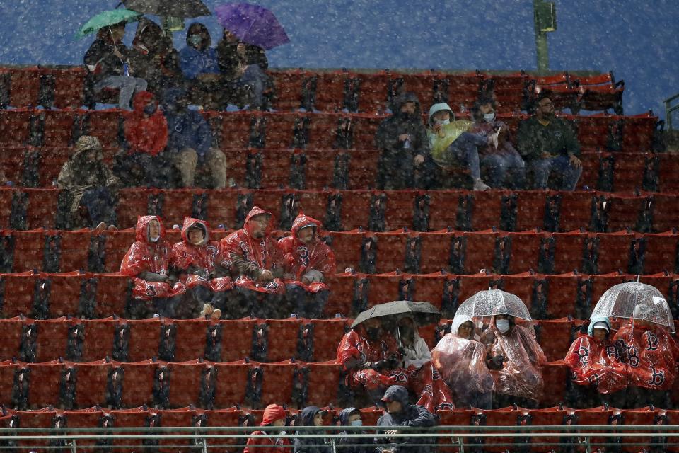 Fans sit in the rain during the third inning of a baseball game between the Boston Red Sox and the Miami Marlins, Friday, May 28, 2021, in Boston. (AP Photo/Michael Dwyer)