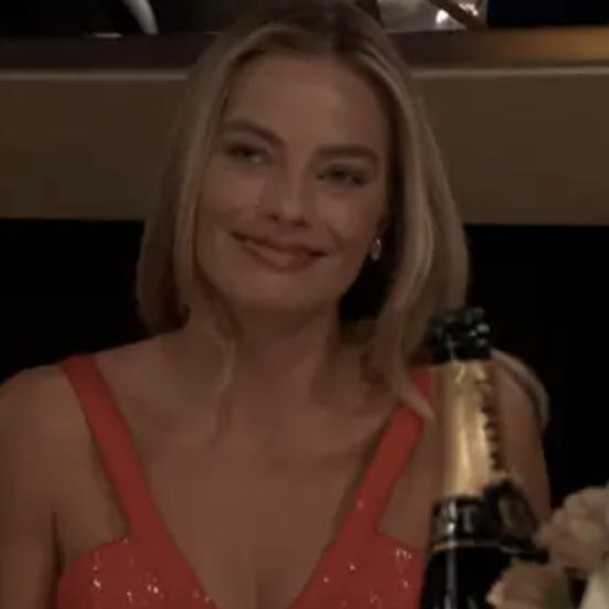 Margot in a sparkling dress, smiling at an event