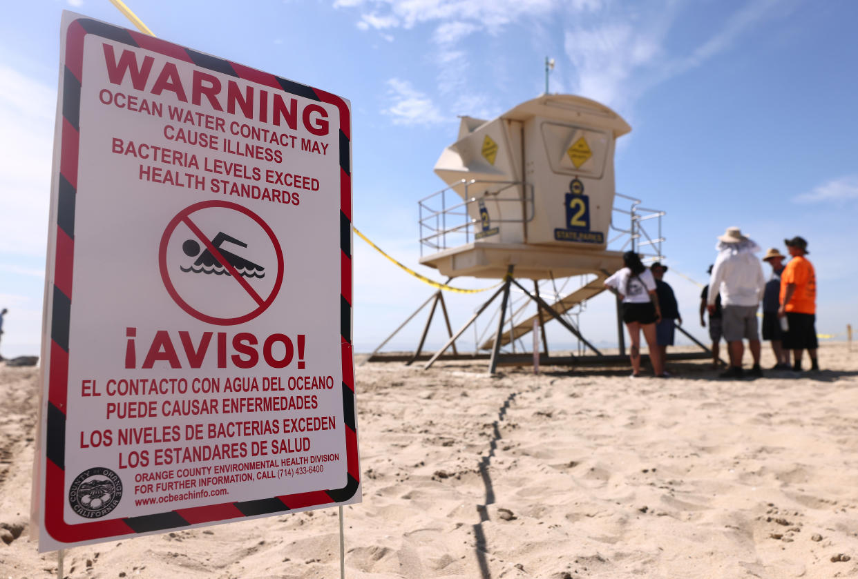 A sign near a lifeguard station on a beach that reads: Warning, ocean water contact may cause illness, bacteria levels exceed health standards