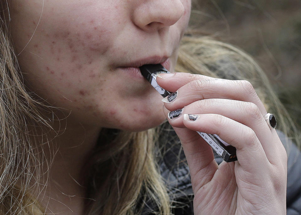 FILE - In this April 11, 2018 file photo, a high school student uses a vaping device near a school campus in Cambridge, Mass. Massachusetts Gov. Charlie Baker is declaring a public health emergency and ordering a four-month temporary ban on all vaping products in the state. The Republican governor made the announcement Tuesday, Sept. 24, 2019 amid growing concern about the health effects of vaping products. (AP Photo/Steven Senne, File)