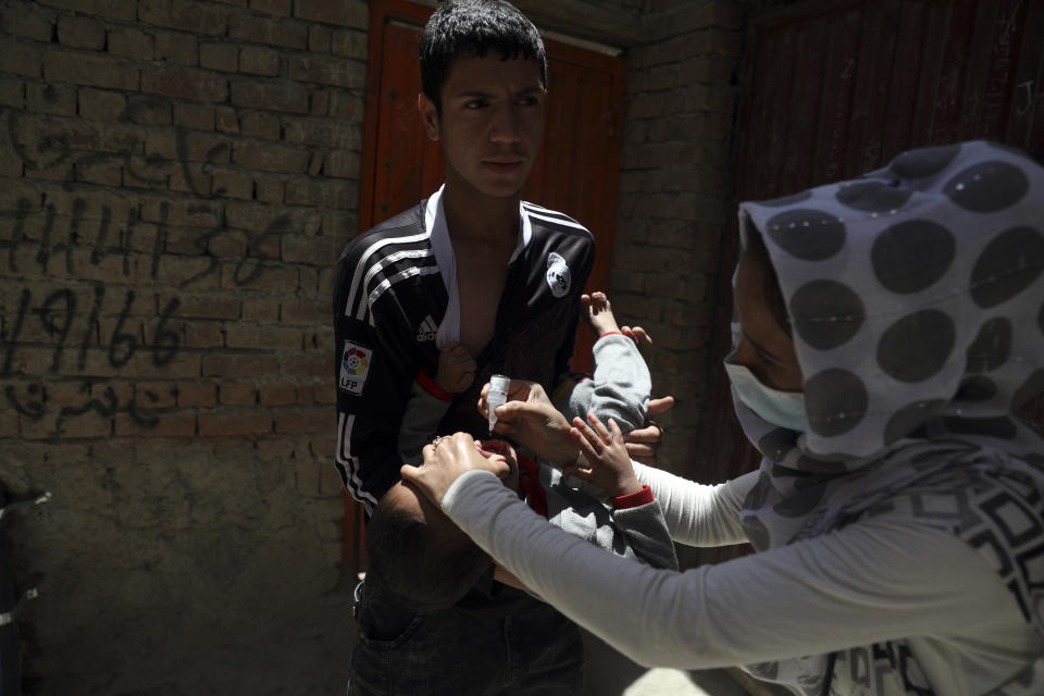 A health worker administers a vaccination to a child during a polio campaign in the old part of Kabul, Afghanistan, Tuesday, June 15, 2021. Gunmen on Tuesday targeted members of polio teams in eastern Afghanistan, killing some staffers, officials said. (AP Photo/Rahmat Gul)