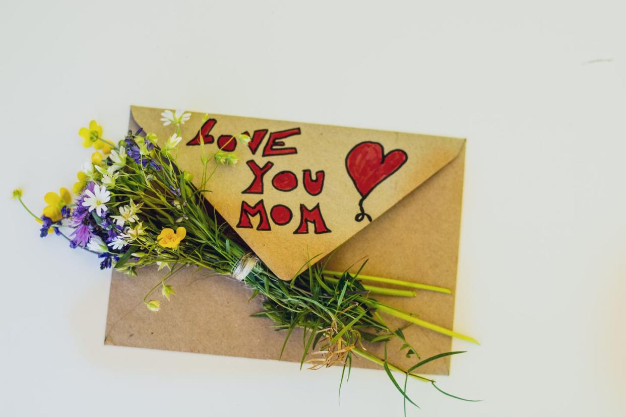 mother's day greeting envelope and a bouquet of flowers, on white background