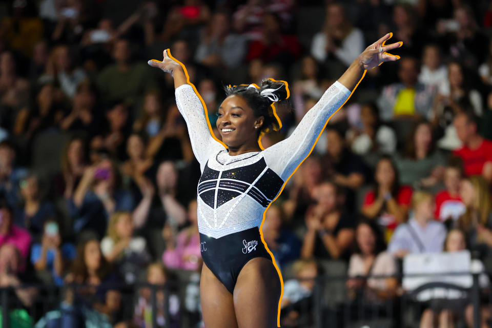 Simone Biles raises her arms in the air during the floor exercise.