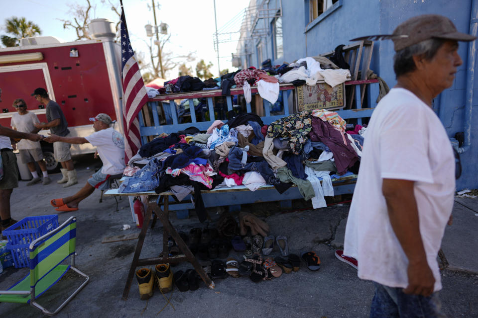 Trabajadores de camaroneros inactivos pasan el tiempo junto a pilas de ropa y zapatos donados para ayudar a un sector que fue vapuleado por el huracán Ian. Foto del 7 de octubre del 2022. (AP Photo/Rebecca Blackwell)