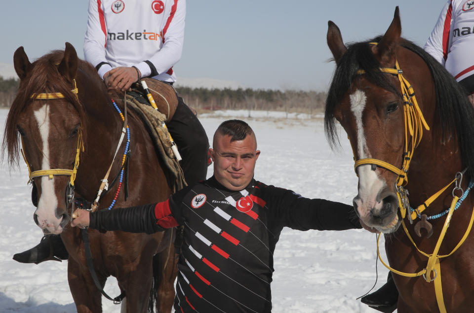 Selcuk Davulcu, 31, a horse groom for the Dadas (Comrades) local sporting club, prepares the horses during a game of Cirit, a traditional Turkish equestrian sport that dates back to the martial horsemen who spearheaded the historical conquests of central Asia's Turkic tribes, between the Comrades and the Experts local sporting clubs, in Erzurum, eastern Turkey, Friday, March 5, 2021. The club officials said that Davulcu, a man with Down syndrome has been communicating with people just for the last four years thanks to the horses as they played a big role on his rehabilitation.The game that was developed more than a 1,000 years ago, revolves around a rider trying to spear his or her opponent with a "javelin" - these days, a rubber-tipped, 100 centimeter (40 inch) length of wood. A rider from each opposing team, which can number up to a dozen players, face each other, alternately acting as the thrower and the rider being chased. Cirit was popular within the Ottoman empire, before it was banned as in the early 19th century. (AP Photo/Kenan Asyali)