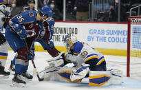 St. Louis Blues goaltender Jordan Binnington, right, makes a save against a shot by Colorado Avalanche left wing Andre Burakovsky (95) in the second period of Game 1 of an NHL hockey Stanley Cup first-round playoff series Monday, May 17, 2021, in Denver. (AP Photo/David Zalubowski)