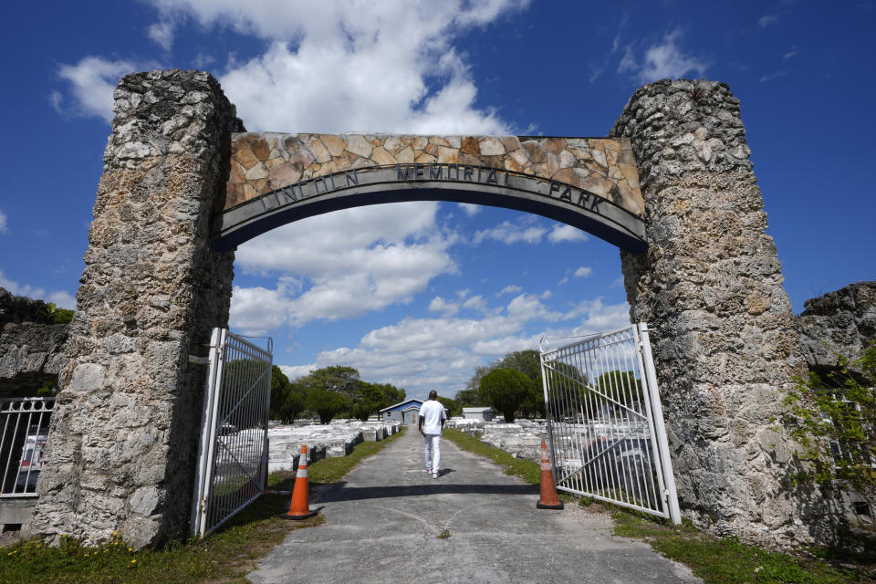 Jessie Wooden, the owner of the Lincoln Park Memorial Cemetery, walks through the front gate Monday, Feb. 26, 2024, in the Brownsville neighborhood of Miami. After Wooden serendipitously met an aunt when he was in his late 40s and learned about his mother's resting place, he tried to visit but found the vast graveyard overgrown, snake-infested and surrounded by debris. (AP Photo/Marta Lavandier)