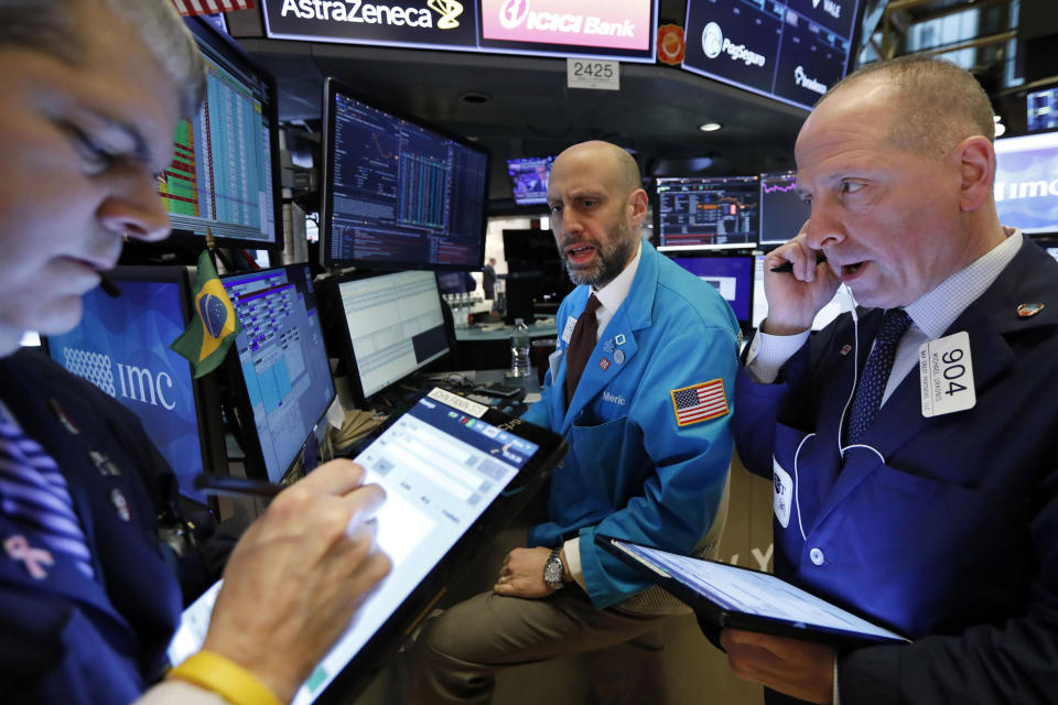 FILE - In this March 12, 2020, file photo, specialist Meric Greenbaum, center, works with traders on the floor of the New York Stock Exchange. U.S. stocks are dipping modestly in early trading Tuesday, July 7, 2020, as expanding coronavirus outbreaks dim hopes for a speedy recovery. (AP Photo/Richard Drew, File)