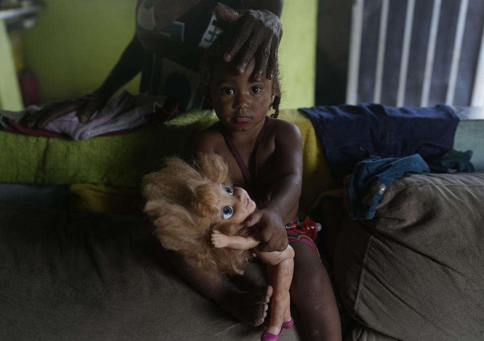 Eloa, 2, looks at the camera as her grandmother Lady Laurentino, 74, caresses her, at their home in the Jardim Gramacho favela of Rio de Janeiro, Brazil, Monday, Oct. 4, 2021. After the recent surge in gas prices, Laurentino says she is cooking with wood these days because she doesn't have money to buy a new gas cylinder. (AP Photo/Silvia Izquierdo)