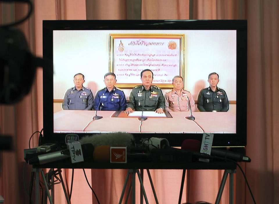 FILE - In this Thursday, May 22, 2014, file photo, Thai Army Chief Gen. Prayuth Chan-ocha, center, and other high ranking Thai officers are shown on television announcing the military takeover in Bangkok, Thailand. Thailand's army chief announced a military takeover of the government Thursday, saying the coup was necessary to restore stability and order after six months of political deadlock and turmoil. They are from left, National Police Chief Gen. Adul Saengsingkaew, Air Force Chief Air Chief Marshal Prachin Chanthong, Prayuth, Navy Chief Adm. Narong Pipatthanasant and an unidentified soldier from the Supreme Command Office. After five years of running Thailand with absolute power, Thailand’s junta leader is seeking to hold on to power through the ballot box.(AP Photo/Apichart Weerawong, File)