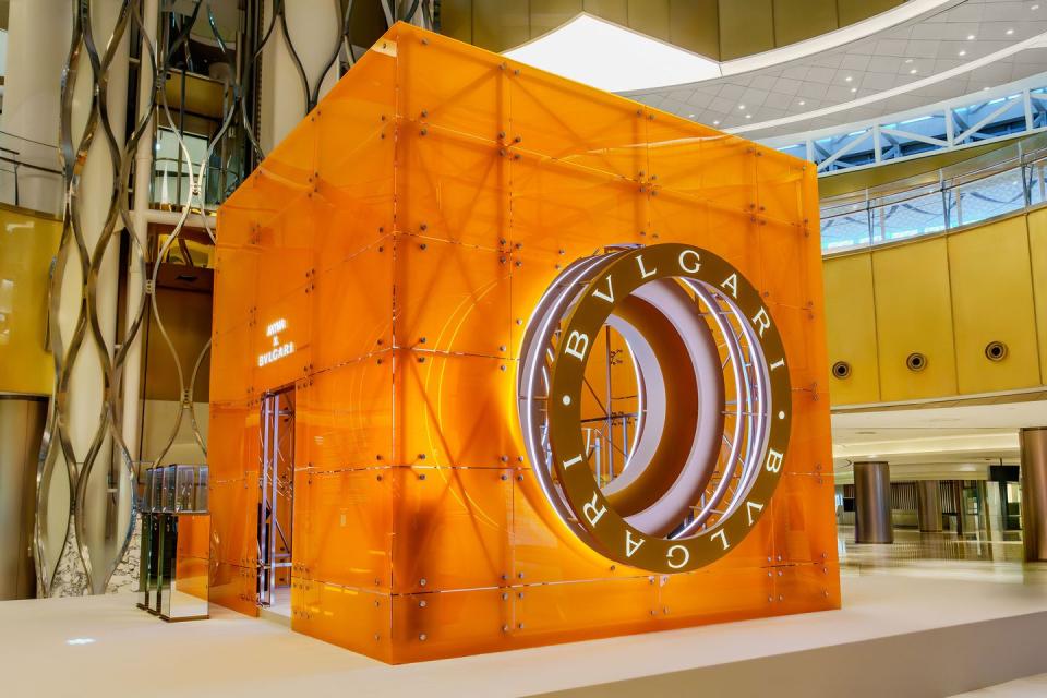 large translucent brightly lit orange cube with a circular opening with the bulgari logo on it