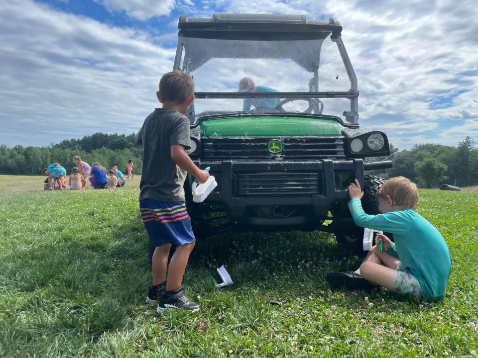 Campers try to stay cool amid 90-degree temperatures by hosing down a tractor at Joppa Hill Farm in Bedford, July 12, 2024.