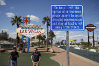 FILE - In this March 21, 2020 file photo, a sign advises people to practice social distancing to slow the spread of the coronavirus at the "Welcome to Fabulous Las Vegas Nevada" sign amid a shutdown of casinos along the Las Vegas Strip in Las Vegas. Nervous travelers, spotty air service, health risks _ the battered global tourism industry is facing unprecedented uncertainty in the wake of the new coronavirus. Millions of workers are laid off or furloughed, and it will likely take years for the industry to get back to the strong demand it was seeing just six months ago. (AP Photo/John Locher, File)