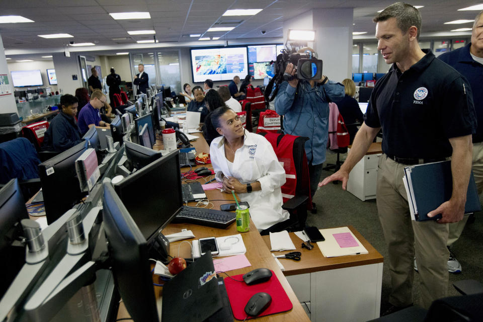 Acting Homeland Security Secretary Kevin McAleenan, right, speaks with FEMA personnel, as he gets information about a storm system, in a visit to the National Response Coordination Center at FEMA headquarters in Washington, Sunday, July 14, 2019. (AP Photo/Jose Luis Magana)