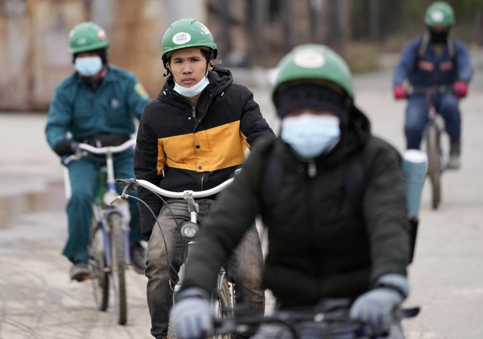 Vietnamese workers ride bicycles on their way to start the work day at the first Chinese car tire factory in Europe near the northern Serbian town of Zrenjanin, 50 kilometers north of Belgrade, Serbia, Thursday, Nov. 18, 2021. Reports have emerged in Serbia of prison-like conditions for some 500 of them at the construction site in north of the country where China's Shandong Linglong Tire Co is building the huge factory. Populist-run Serbia is a key spot for China's expansion and investment policies in Europe and Chinese companies have kept a tight lid on their projects in the country amid reports of disrespect of the Balkan nation's anti-pollution laws and labor regulations. (AP Photo/Darko Vojinovic)