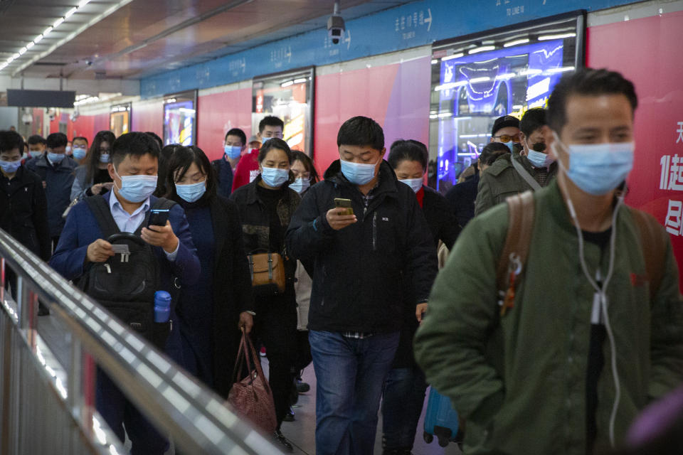 Commuters look at their smartphones as they walk through a subway station in Beijing, Thursday, Oct. 29, 2020. China's leaders vowed Thursday to speed up its development as a self-reliant "technology power" amid a feud with Washington that is cutting access to U.S. components and hampering Beijing's industrial ambitions. (AP Photo/Mark Schiefelbein)