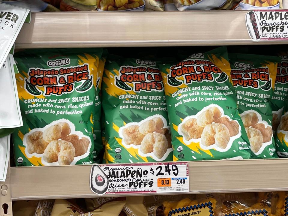 Green bags of Trader Joe's jalapeño seasoned corn and rice puffs on a shelf at Trader Joe's