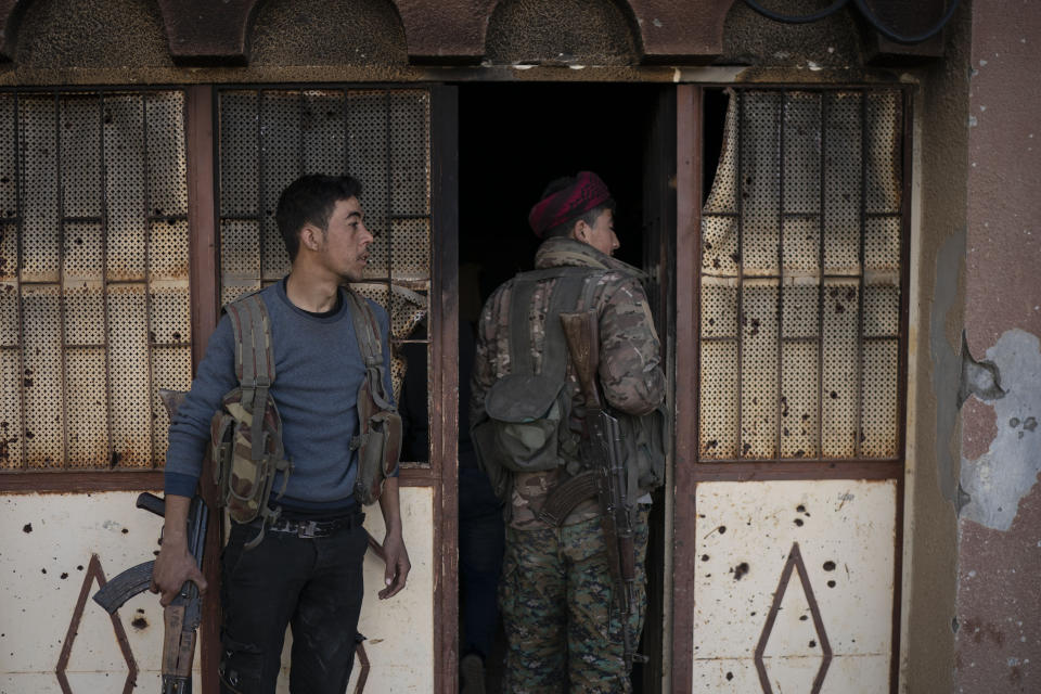 U.S.-backed Syrian Democratic Forces (SDF) fighters enter a building used as a temporary base near the last land still held by Islamic State militants in Baghouz, Syria, Monday, Feb. 18, 2019. Hundreds of Islamic State militants are surrounded in a tiny area in eastern Syria are refusing to surrender and are trying to negotiate an exit, Syrian activists and a person close to the negotiations said Monday. (AP Photo/Felipe Dana)