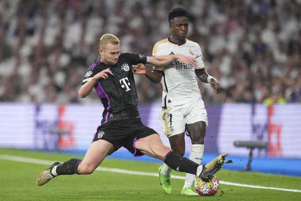 Real Madrid's Vinicius Junior, right, is challenged by Bayern's Matthijs de Ligt during the Champions League semifinal second leg soccer match between Real Madrid and Bayern Munich at the Santiago Bernabeu stadium in Madrid, Spain, Wednesday, May 8, 2024. (AP Photo/Manu Fernandez)