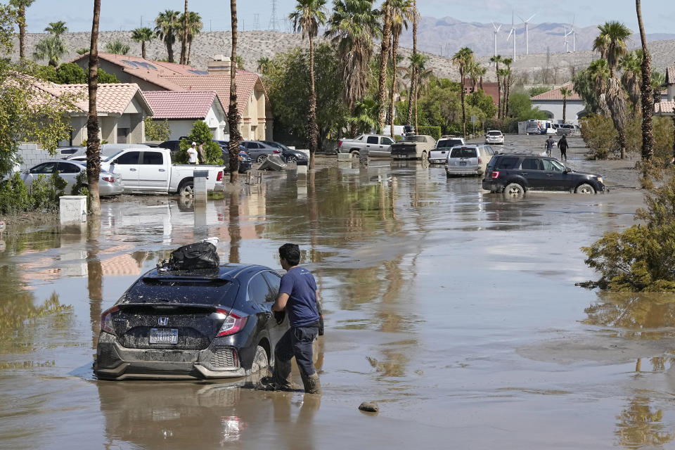 Dorian Padilla stands at his car as he waits for a tow after it got stuck in the mud on a street Monday, Aug. 21, 2023, in Cathedral City, Calif. Forecasters said Tropical Storm Hilary was the first tropical storm to hit Southern California in 84 years, bringing the potential for flash floods, mudslides, isolated tornadoes, high winds and power outages. (AP Photo/Mark J. Terrill)