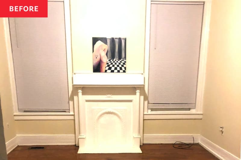 Empty bedroom with white mantel, pale yellow walls, and wood flooring.