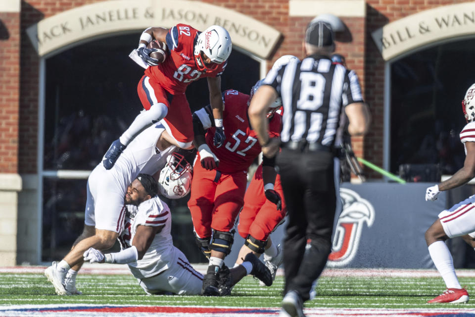 Liberty's Aaron Bedgood (82) runs over UMass defenders for a first down during the first half of an NCAA college football game, Saturday, Nov. 18, 2023, in Lynchburg, Va. (AP Photo/Robert Simmons)