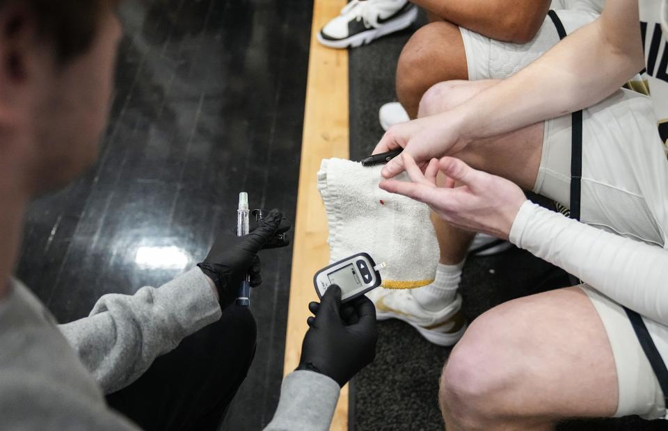 Noblesville Millers Aaron Fine (3) checks his blood sugar Tuesday, Feb. 20, 2024, ahead of the game against Mississinewa at Noblesville High School in Noblesville.