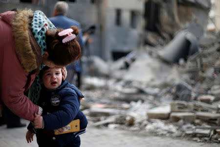 A Palestinian woman comforts her son outside their destroyed house after Israeli air strikes targeted a nearby Hamas site on Monday, in Gaza City March 27, 2019. REUTERS/Mohammed Salem