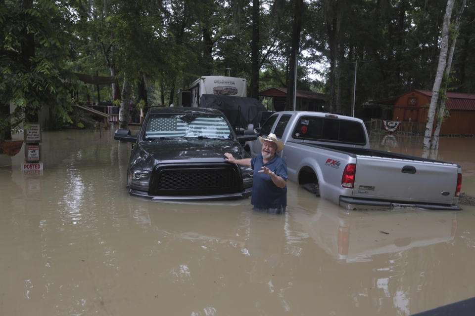 A man waves at Texas Parks & Wildlife Department game wardens as they arrive by boat to rescue residents from floodwaters in Liberty County, Texas, on Saturday, May 4, 2024. (AP Photo/Lekan Oyekanmi)