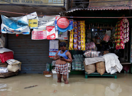 A man checks his mobile phone as he stands in a waterlogged street after rainfall in Kolkata, India, July 26, 2017. REUTERS/Rupak De Chowdhuri