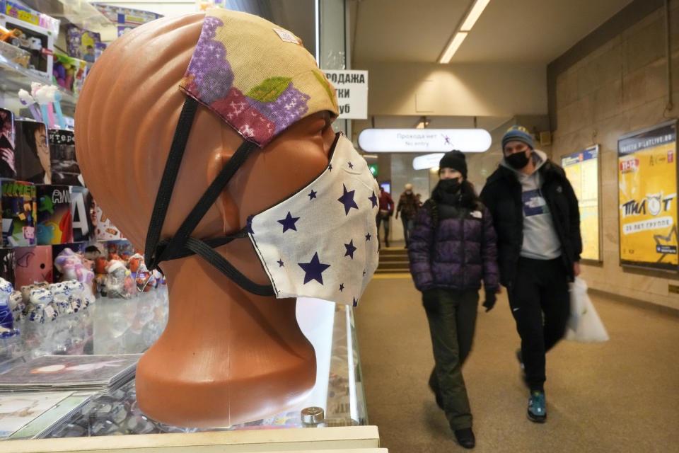 People walk past face masks displayed for sale in St. Petersburg, Russia, Monday, Jan. 24, 2022. Daily new coronavirus infections in Russia have reached an all-time high and authorities are blaming the highly contagious omicron variant, which they expect to soon dominate the country's outbreak. (AP Photo/Dmitri Lovetsky)