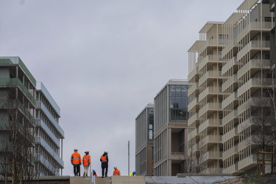 Workers stand among the buildings of the Olympic village, in Saint-Denis, north of Paris Wednesday, Feb. 28, 2024. When French President Emmanuel Macron inaugurates the Olympic village on Thursday, Feb. 29, he will see a run-down area transformed into an international hub for the Paris Games. (AP Photo/Thibault Camus)