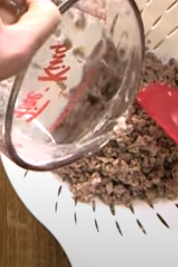 Pouring water over cooked ground beef in a colander