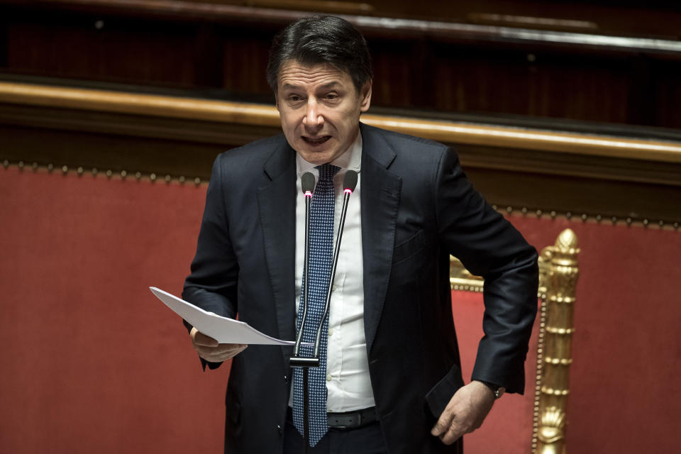 Italian Premier Giuseppe Conte adjusts his jacket as he refers to parliament on the ongoing Covid-19 situation, in Rome, Thursday, March 26, 2020. After more than two weeks of a nationwide lockdown to halt the spread of the coronavirus, the Italian government decided to expand the mandatory closure of nonessential commercial activities to heavy industry in the eurozone's third-largest economy, a major exporter of machinery, textiles and other goods. The new coronavirus causes mild or moderate symptoms for most people, but for some, especially older adults and people with existing health problems, it can cause more severe illness or death. (Roberto Monaldo/LaPresse via AP)