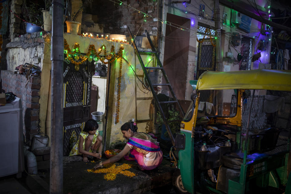 A woman and her daughter make a rangoli, a traditional decoration, at the entrance to their home during Diwali celebrations in New Delhi, India, Thursday, Nov. 4, 2021. Diwali, the festival of lights, is one of Hinduism's most important festivals dedicated to the worship of Lakshmi, the Hindu goddess of wealth. (AP Photo/Altaf Qadri)