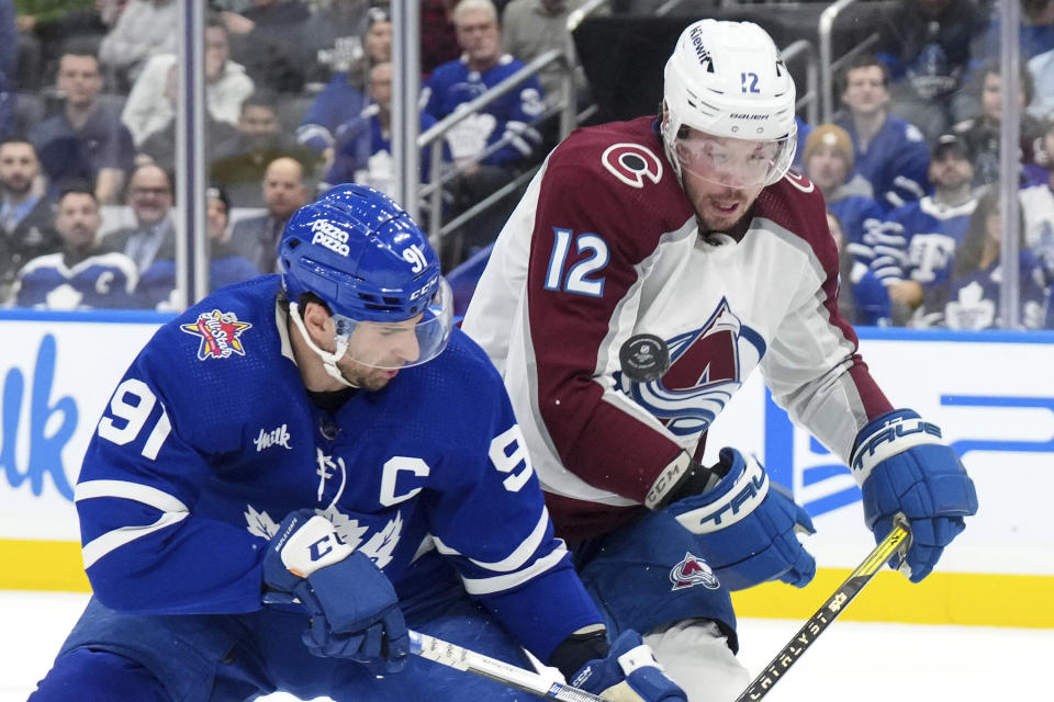 Toronto Maple Leafs center John Tavares (91) vies for control of the puck with Colorado Avalanche center Ryan Johansen (12) during the second period of an NHL hockey game in Toronto, Saturday, Jan. 13, 2024. (Chris Young/The Canadian Press via AP)