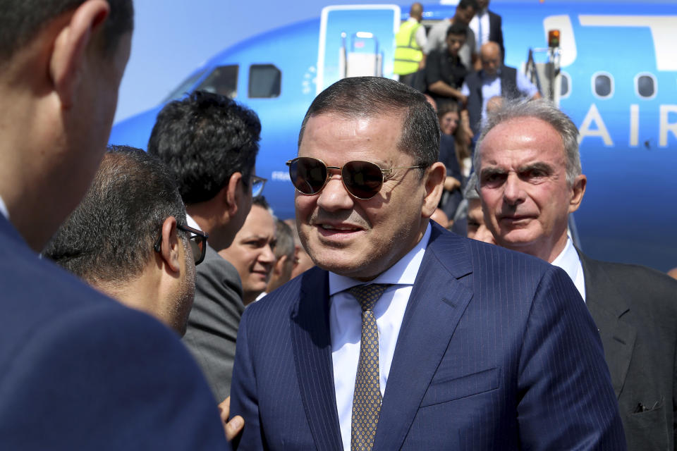 The prime minister of one of Libya's rival administrations, Abdul-Hamid Dbeibah, center, shakes hands during his arrival in Tripoli, Libya, July 24, 2023, after the first direct flight between Italy and Libya in nearly a decade by a commercial airline. Oil-rich Libya plunged into chaos after a NATO-backed uprising toppled and killed longtime dictator Moammar Gadhafi in 2011. In the disarray that followed, the country split into rival administrations in the east and west, each backed by rogue militias and foreign governments, and much of the country's international air connections were cancelled. (AP Photo/Yousef Murad)