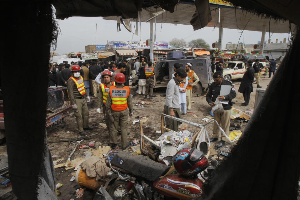 Pakistani police officers and volunteers visit the site of a blast in Peshawar, Pakistan, Friday, March 14, 2014. Pakistani officials said a suicide attacker has blown himself up near a police armored vehicle outside the northwestern city of Peshawar, killing several people. (AP Photo/Mohammad Sajjad)