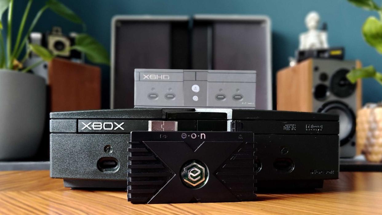  Eon XBHD next to original Xbox on woodgrain table. 