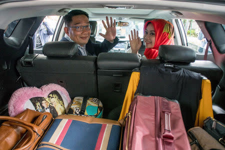 Bandung Major Ridwan Kamil and his wife Atalia Kamil wave to reporters as they sit in his car in Bandung, Indonesia January 20, 2018. Picture taken January 20, 2018. Antara Foto/Novrian Arbi via REUTERS