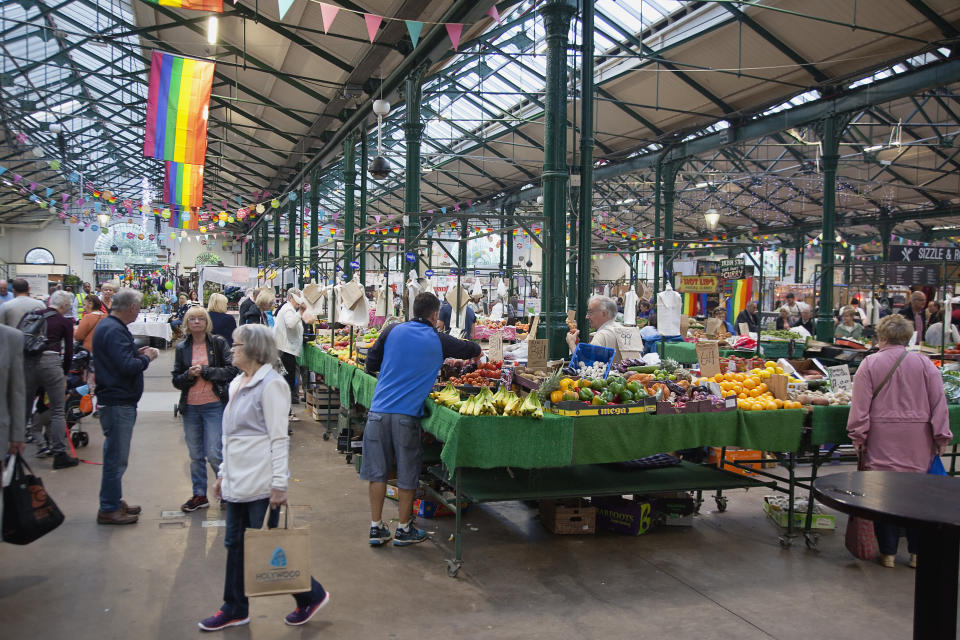 Ireland, North, Belfast, St George's Market interior, Fruit and veg stalls with rainbow flags above. (Photo by: Eye Ubiquitous/UIG via Getty Images)