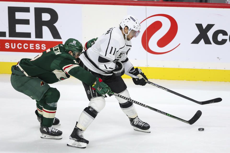 Los Angeles Kings center Anze Kopitar, right, skates with the puck while Minnesota Wild defenseman Jake Middleton (5) defends during the third period of an NHL hockey game Thursday, Oct. 19, 2023, in St. Paul, Minn. (AP Photo/Matt Krohn)