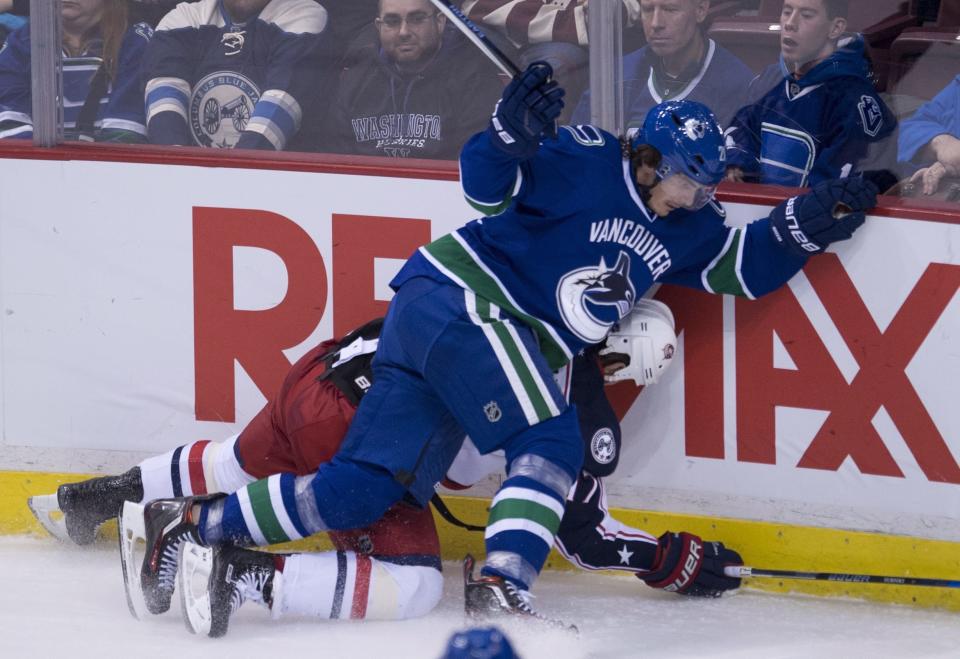 Vancouver Canucks left wing Loui Eriksson (21) puts Columbus Blue Jackets center Brandon Dubinsky (17) into the boards during the third period of an NHL hockey game, Sunday, Dec. 18, 2016 in Vancouver, British Columbia. (Jonathan Hayward/The Canadian Press via AP)