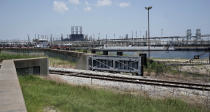 A flood gate and seawall that will be increased is shown near a refinery Thursday, July 26, 2018, in Port Arthur, Texas. The oil industry wants the government to help protect some of its facilities on the Texas Gulf Coast against the effects of global warming. One proposal involves building a nearly 60-mile “spine” of flood barriers to shield refineries and chemical plants. Many Republicans argue that such projects should be a national priority. But others question whether taxpayers should have to protect refineries in a state where top politicians still dispute whether climate change is real. (AP Photo/David J. Phillip)