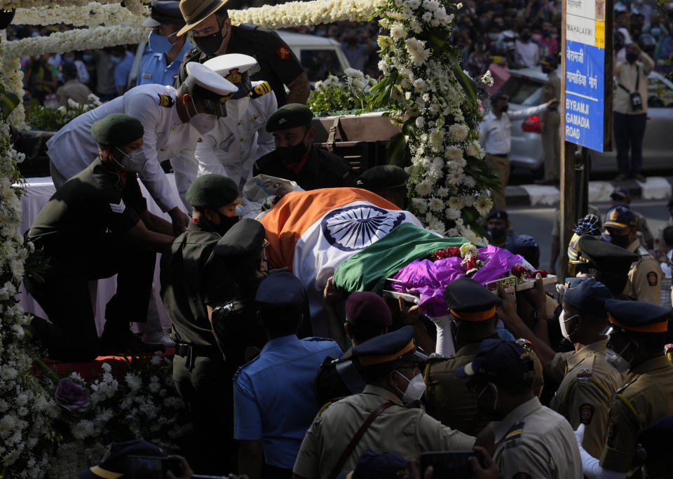 Defense forces and police carry the body of Lata Mangeshkar, outside her home in Mumbai, India, Sunday, Feb.6, 2022. The legendary Indian singer with a prolific, groundbreaking catalog and a voice recognized by a billion people in South Asia, died Sunday morning of multiple organ failure. She was 92. (AP Photo/Rafiq Maqbool)