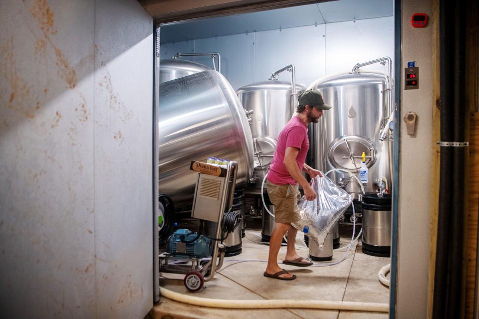 Robert Lemery, founder of The River Arts District Brewing Company, in a refrigerator in the basement of the building, July 29, 2024. The Brite tank to the left was raised and tipped by flood waters.